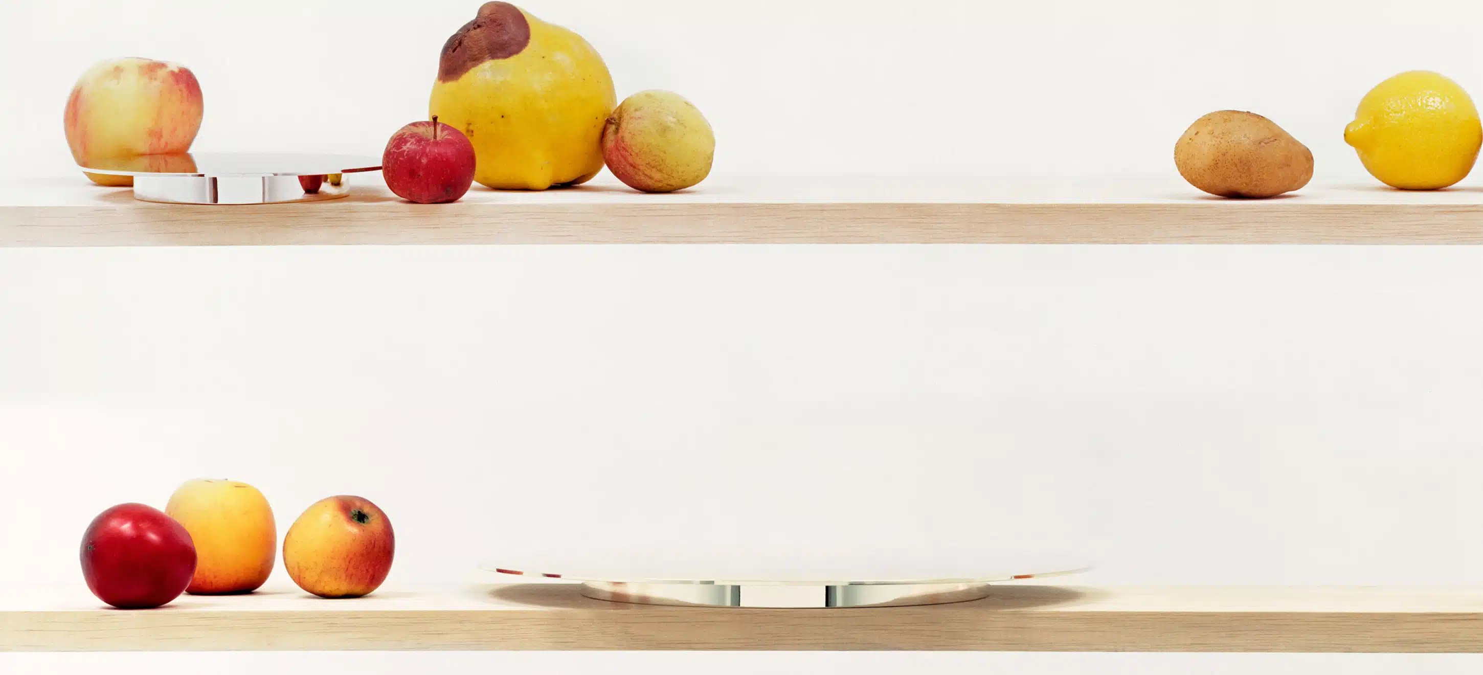 Bread plate and presentation plate from Dinner Service collection on two different shelves, standing next to fruits