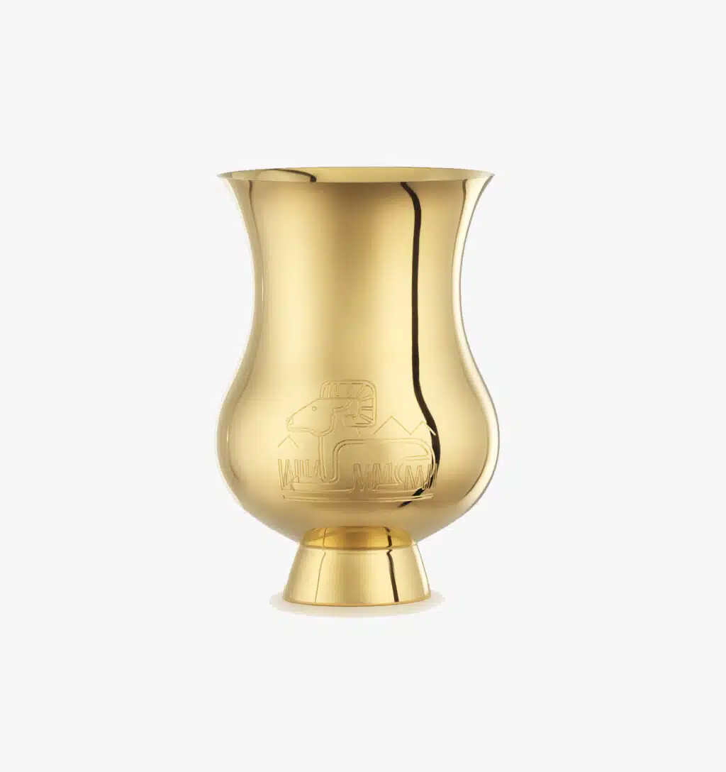 Tumbler gold-gilt engraved with the zodiac sign of the "Year of the Goat" from the Pour le champagne collection by Puiforcat on a light background.