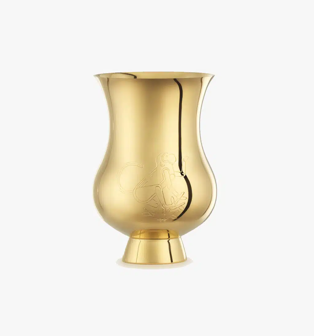 Tumbler gold-gilt engraved with the zodic sign of the "Year of the Monkey" from the Pour le champagne collection by Puiforcat on a light background.