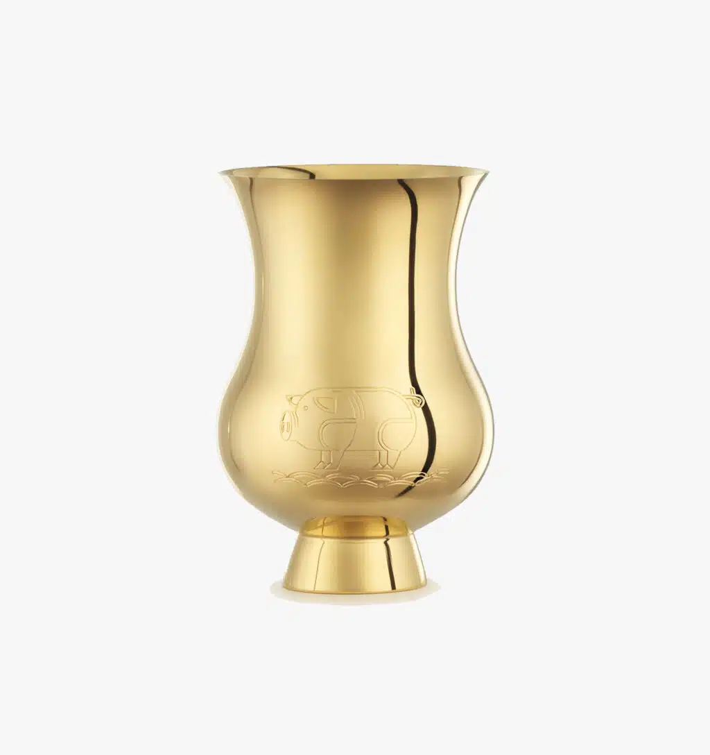 Tumbler gold-gilt engraved with the zodic sign of the "Year of the Pig" from the Pour le champagne collection by Puiforcat on a light background.