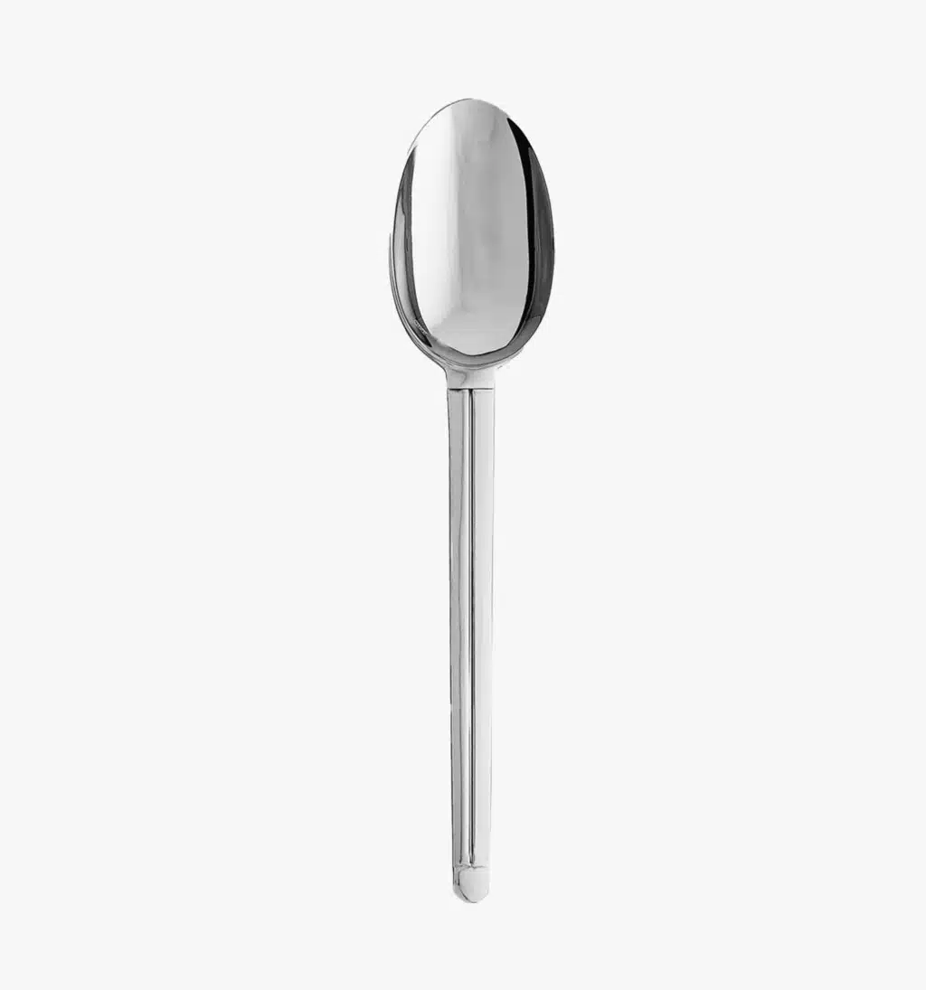 Solid steel serving spoon from the Guéthary collection by Puiforcat on a light background.