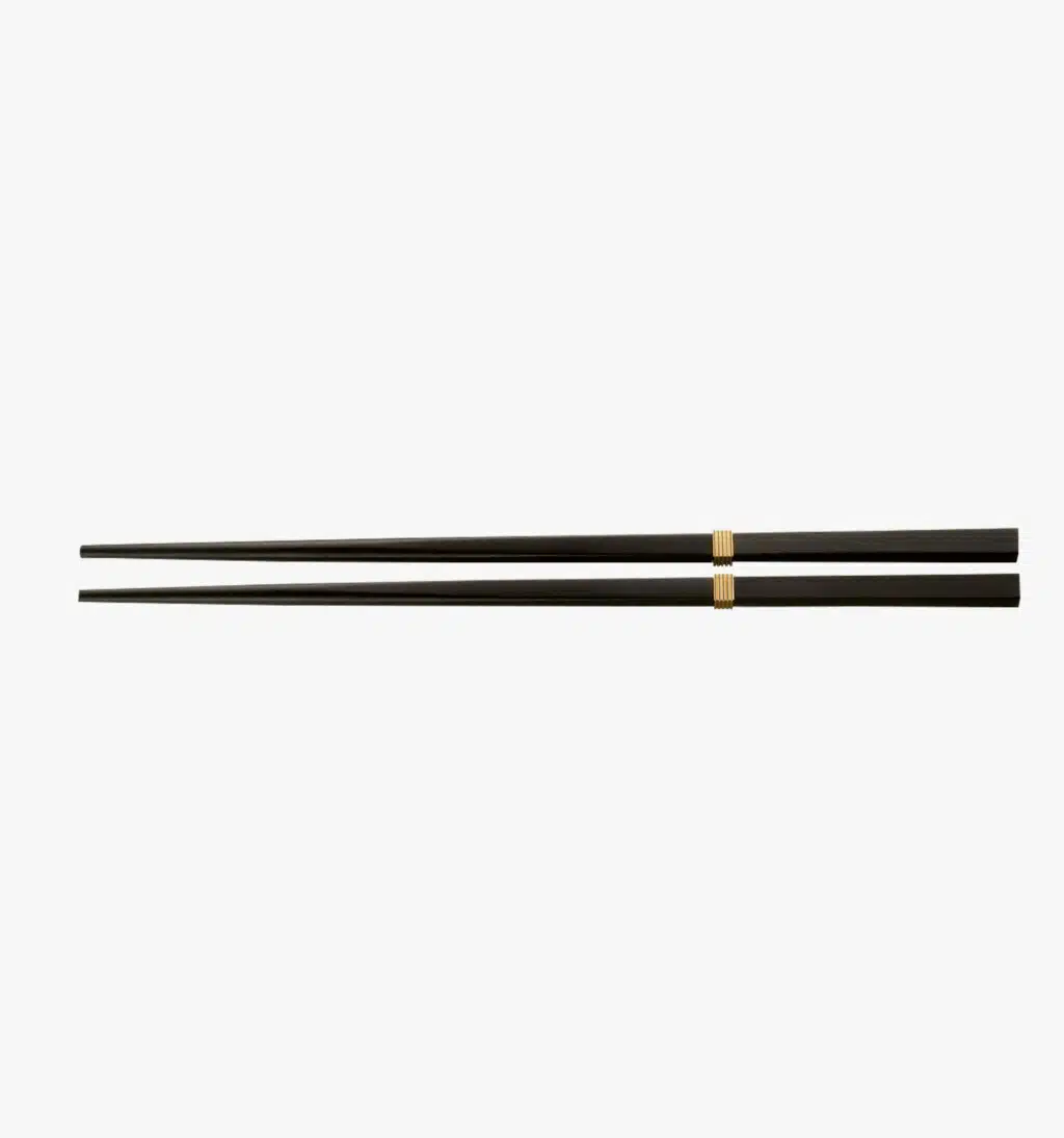 Gold-plated pair of chopsticks from the Croisette collection by Puiforcat on a light background.