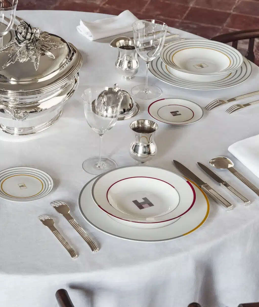 Visuel de table dressée avec le service de table Monogrammes et couverts en argent Puiforcat sur nappe blanche.